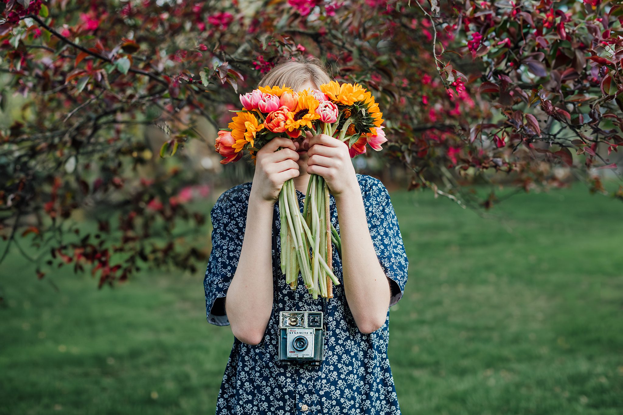 child with flowers under apple tree